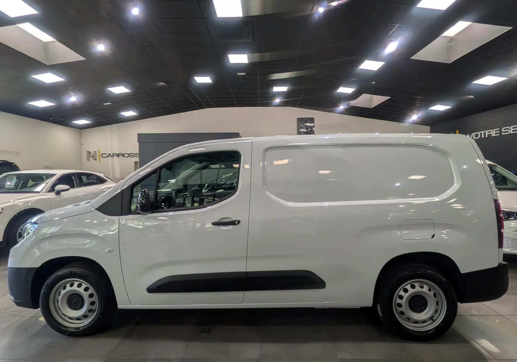 Vue de profil côté gauche d'un Toyota Proace City Long blanc Glacier, fourgon utilitaire avec jantes acier et poignées noires.