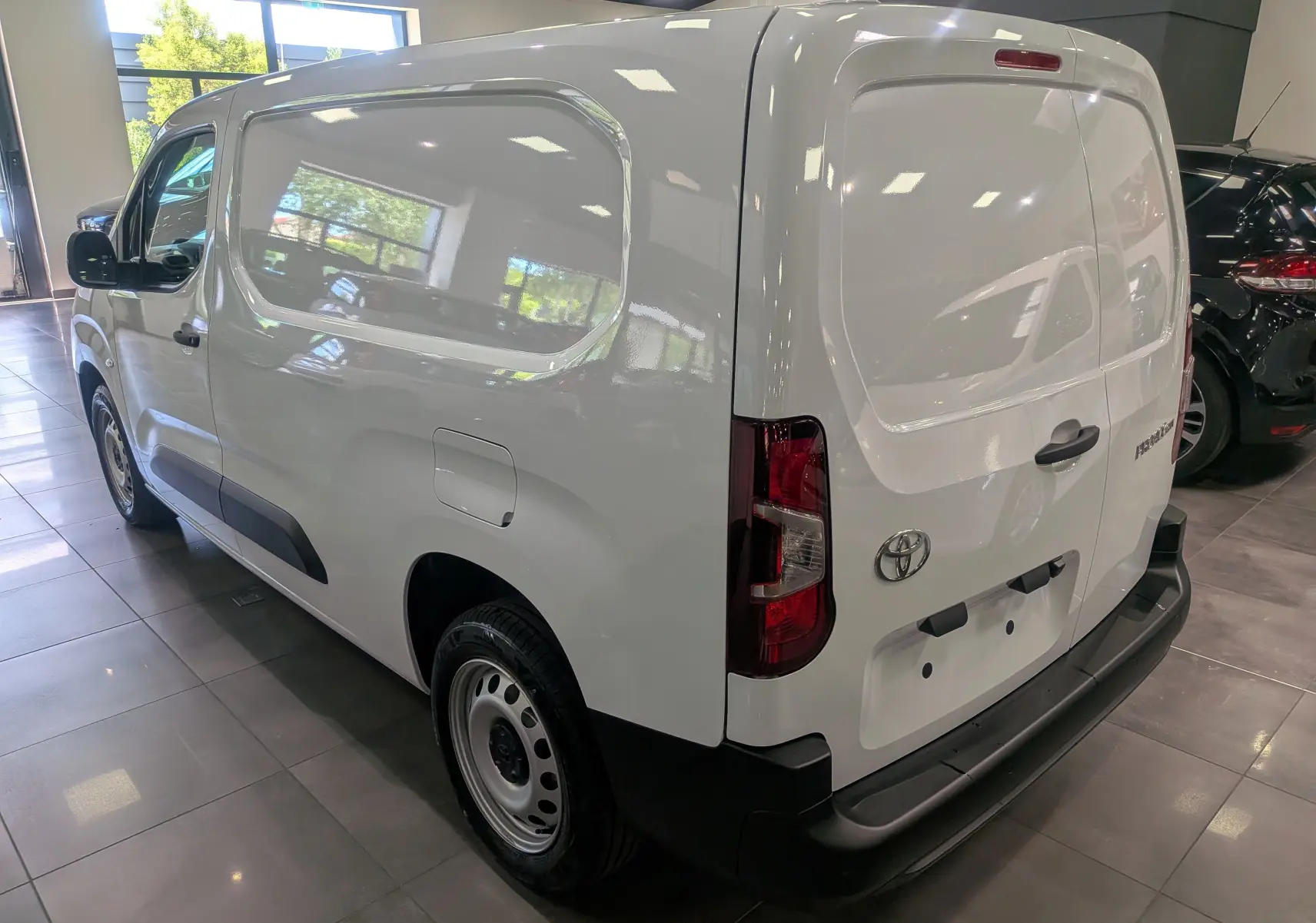 Vue 3/4 arrière droite du Toyota Proace City Long blanc Glacier, fourgon utilitaire avec hayon arrière et protections noires.