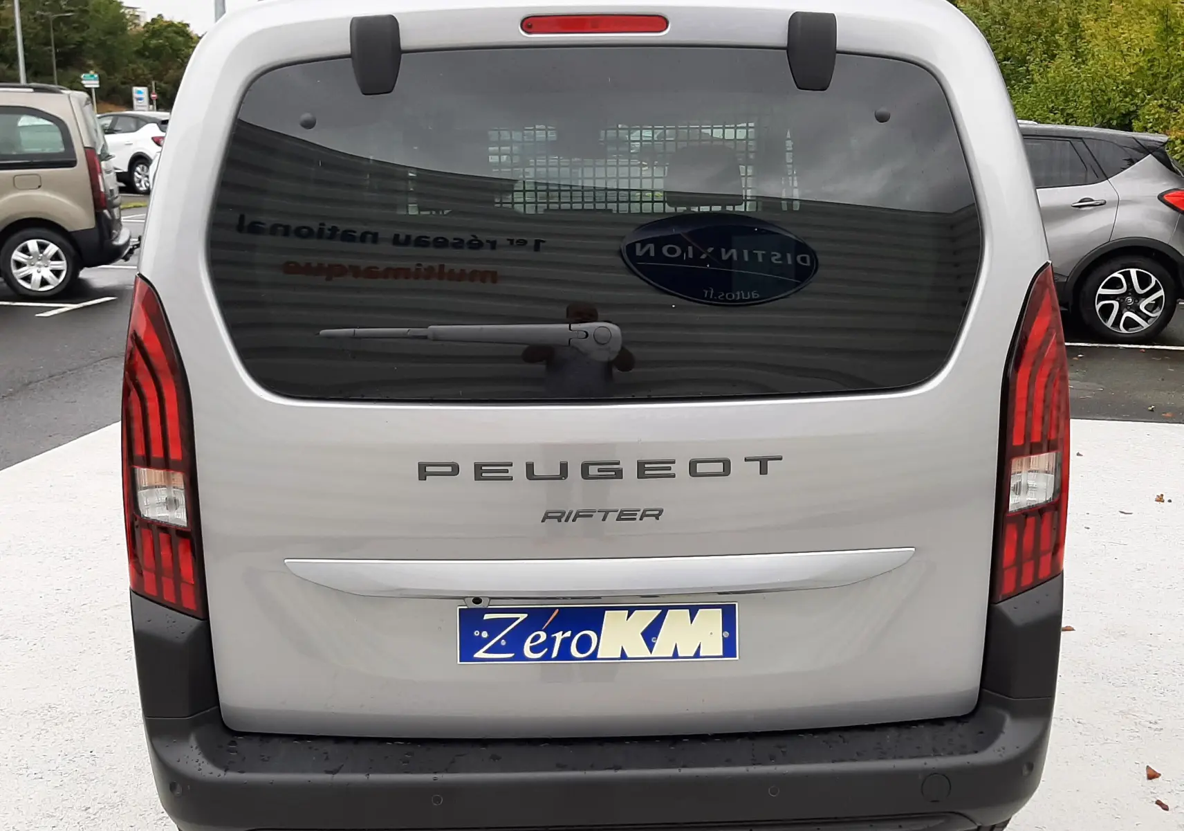 Vue arrière d'un Peugeot Rifter gris acier 2026 avec hayon, feux verticaux rouges et pare-chocs noir mat.