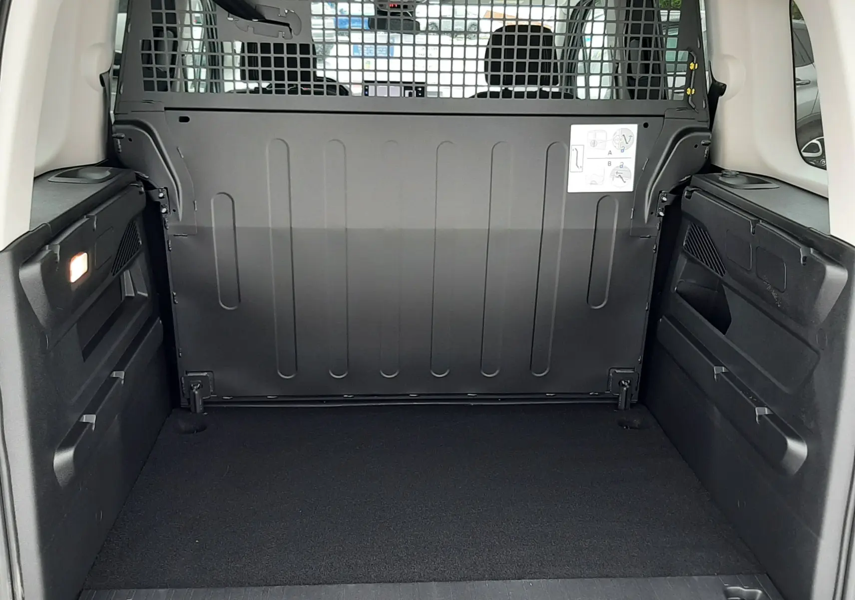 Vue arrière du coffre spacieux et vide du Peugeot Rifter gris acier, avec cloison métallique de séparation visible.