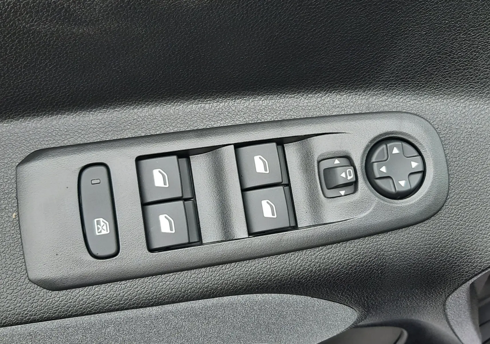 Gros plan sur les commandes électriques des vitres et rétroviseurs sur la porte côté gauche du Peugeot Rifter gris acier 2026.