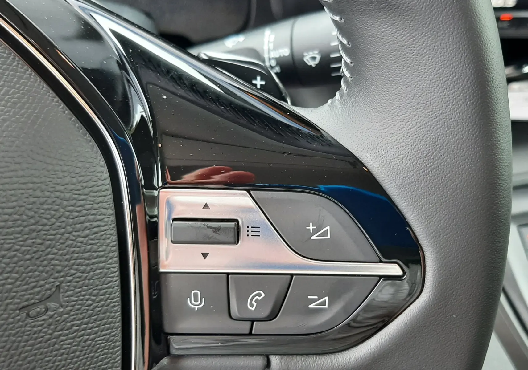 Gros plan sur les commandes multifonctions à droite du volant en cuir gris du Peugeot Rifter gris acier 2026.