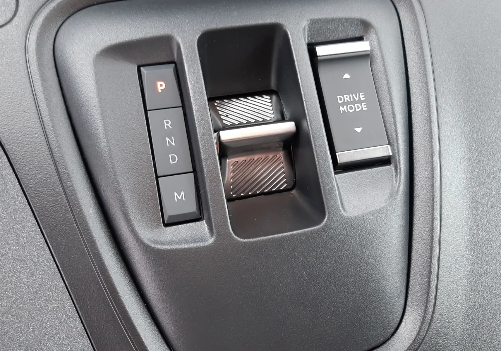 Gros plan sur la console centrale noire du Peugeot Rifter III Ph.2 avec commandes boîte auto et sélecteur Drive Mode.