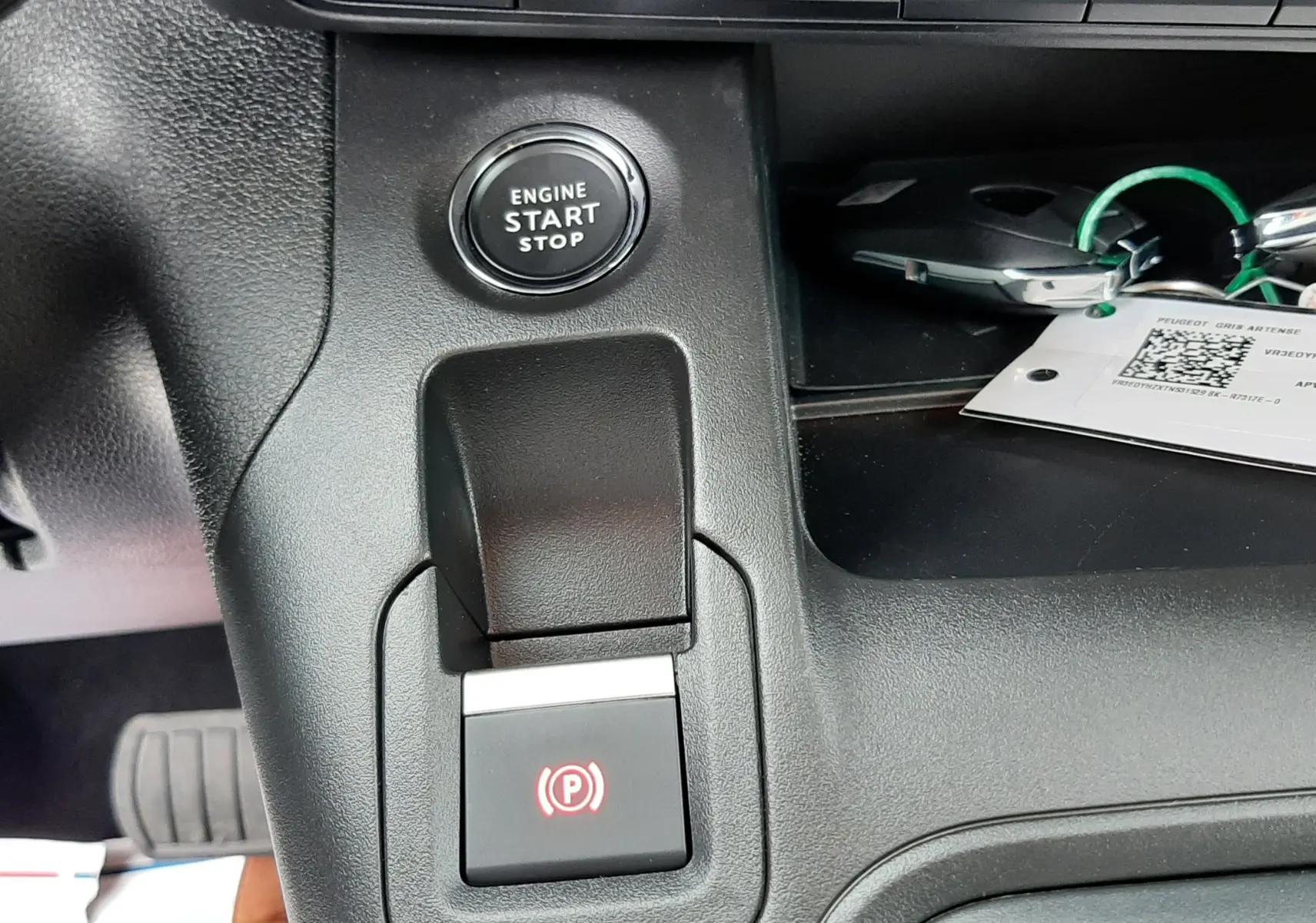 Gros plan intérieur sur la console centrale du Peugeot Rifter gris acier, montrant le bouton start/stop et frein à main électrique.