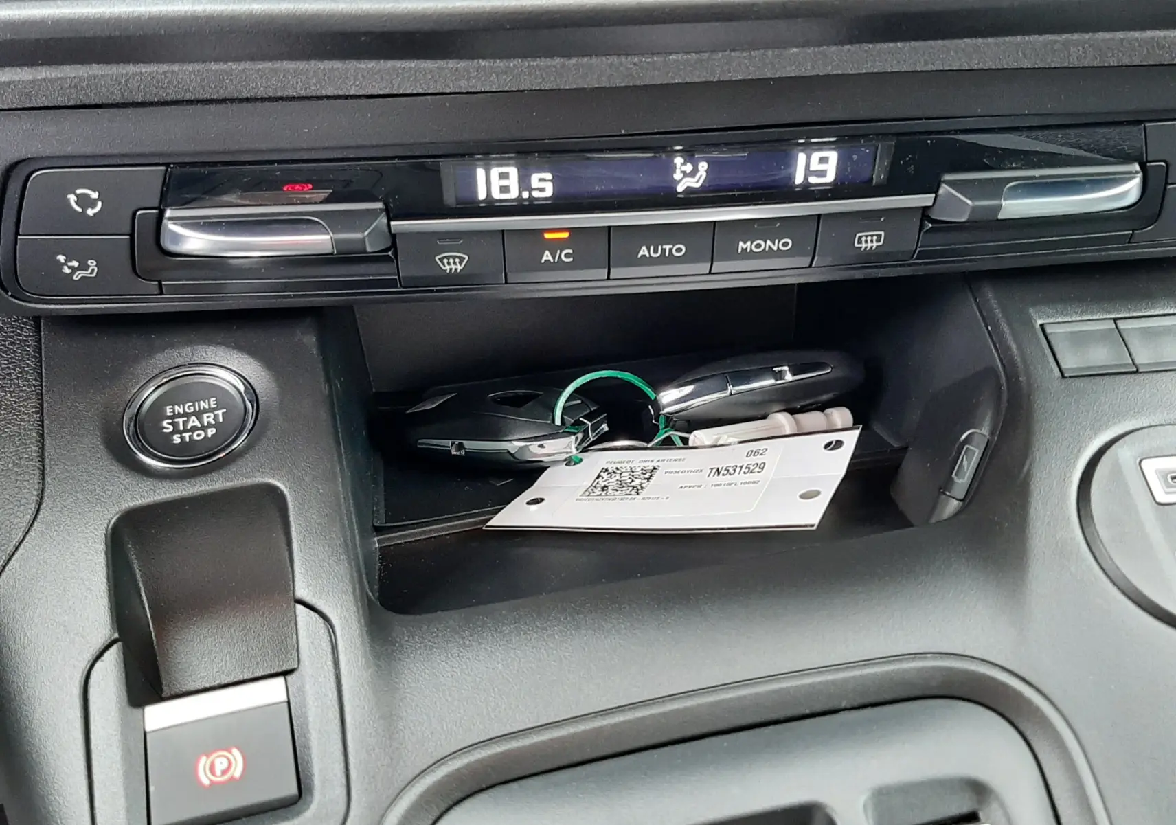 Détail de la console centrale du Peugeot Rifter gris acier 2026, montrant les commandes de climatisation et le bouton start/stop.