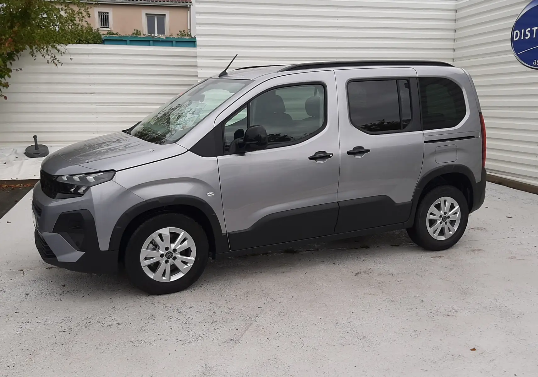 Peugeot Rifter gris acier vu de profil côté gauche, avec porte coulissante et jantes alu 16 pouces.