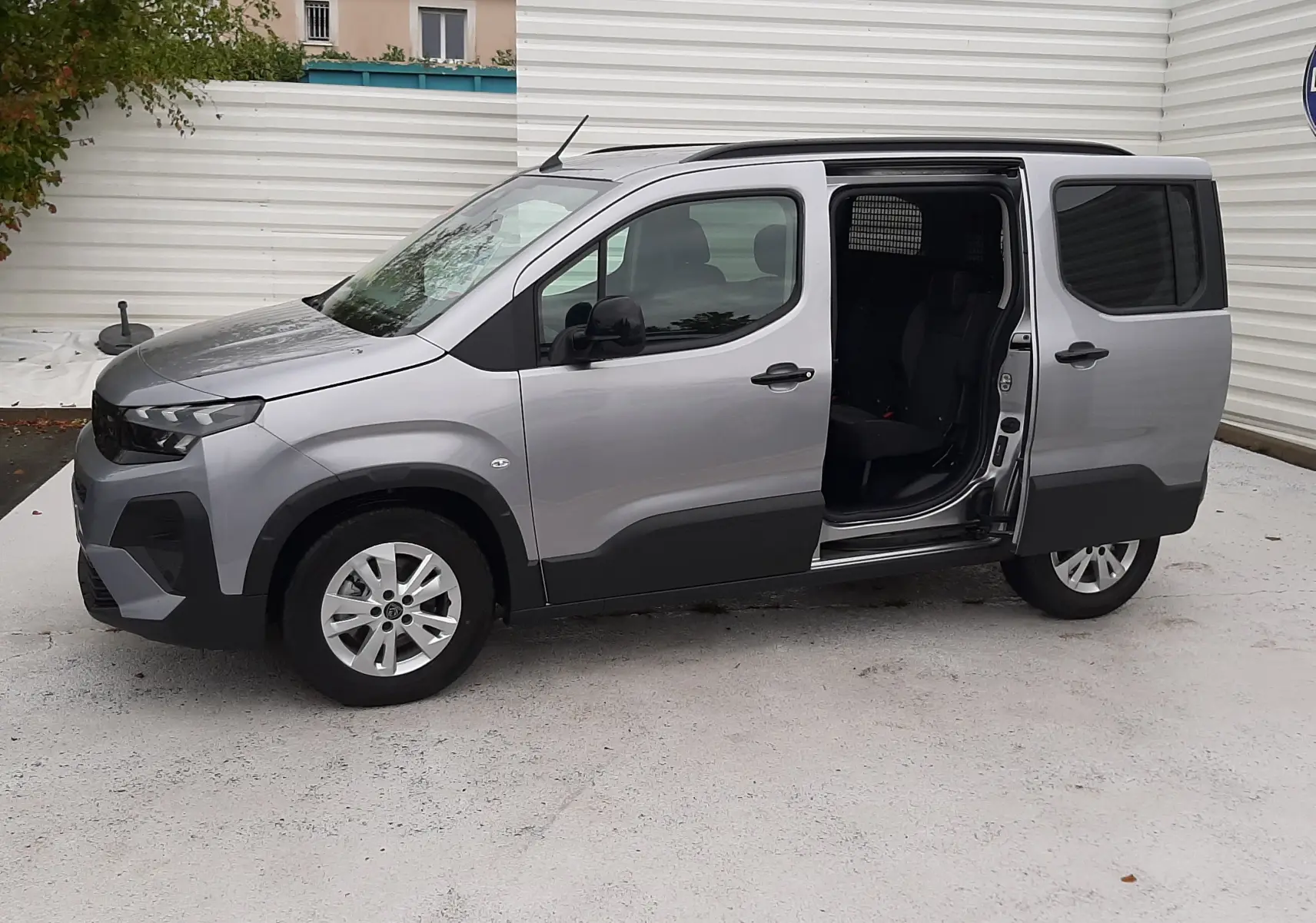 Peugeot Rifter gris acier vu de profil gauche, porte latérale coulissante ouverte, jantes alu 16 pouces visibles.