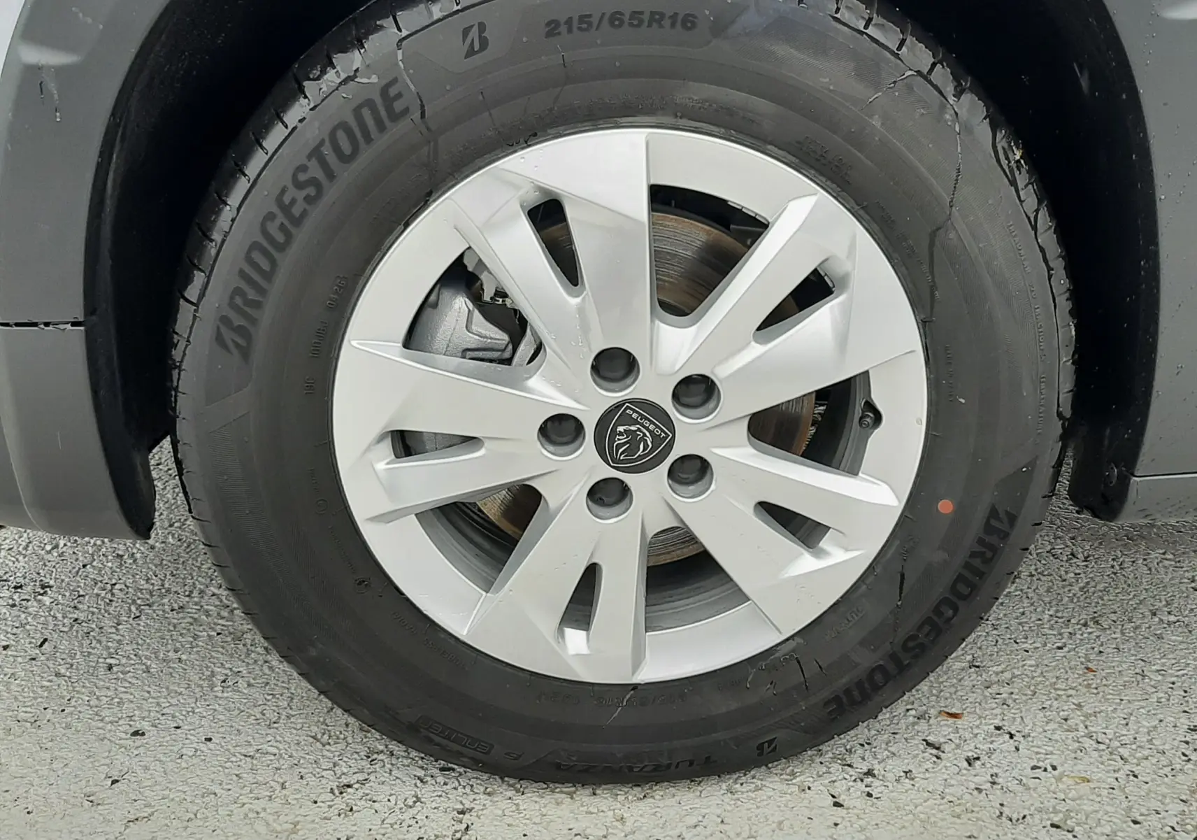 Gros plan sur la roue avant droite du Peugeot Rifter gris acier, avec jante alu 16 pouces et pneu Bridgestone.