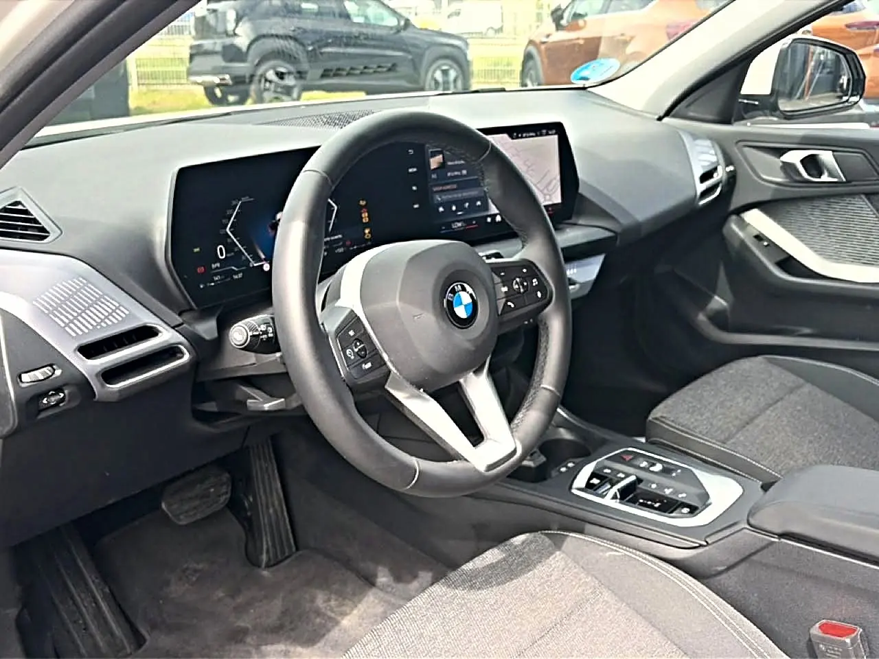 Vue intérieure côté conducteur de la BMW Série 1 120da 2025 avec volant cuir M et écran numérique moderne.