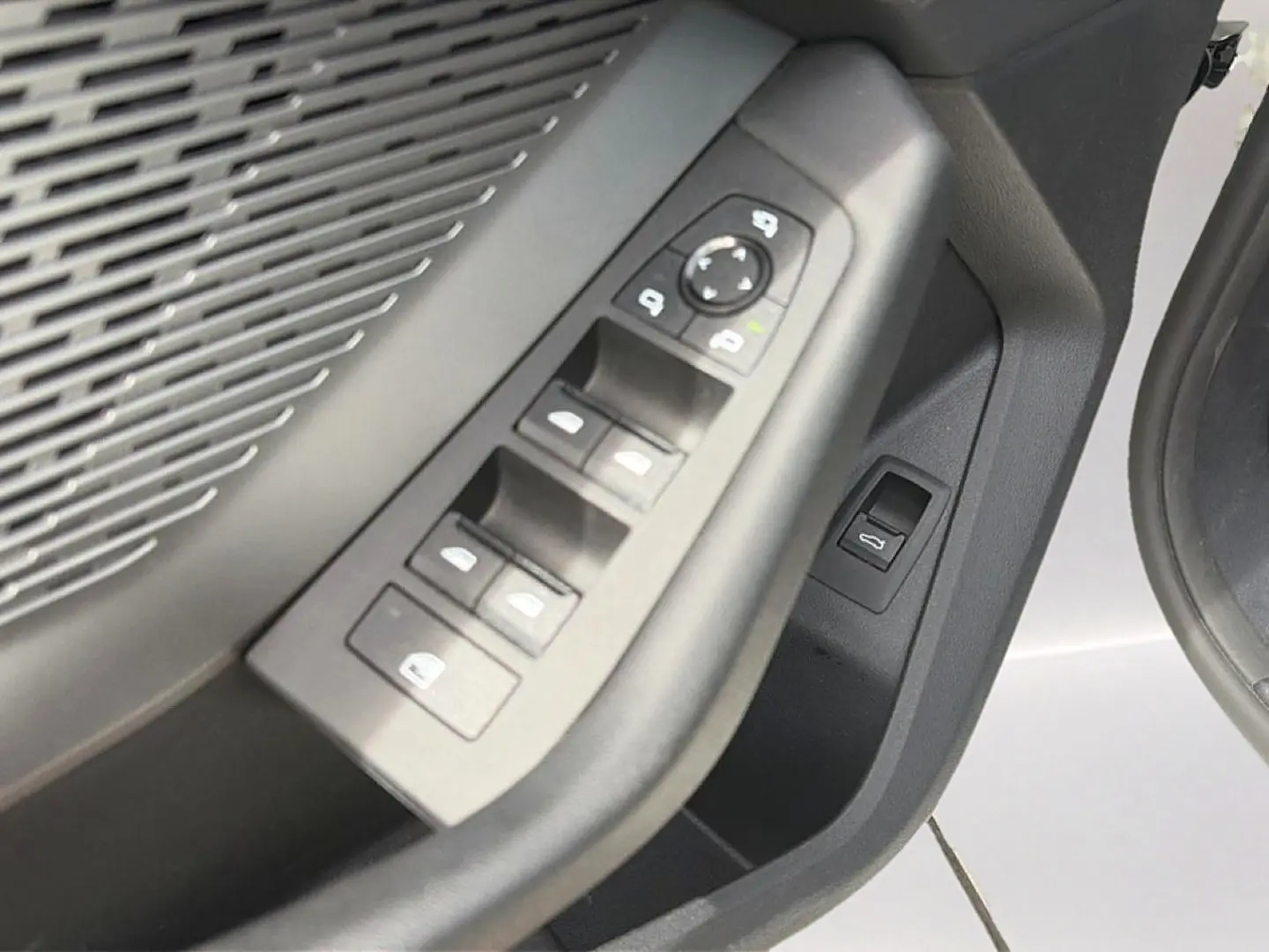 Gros plan sur les commandes des vitres et rétroviseurs côté conducteur d'une BMW Série 1 blanche, intérieur noir.