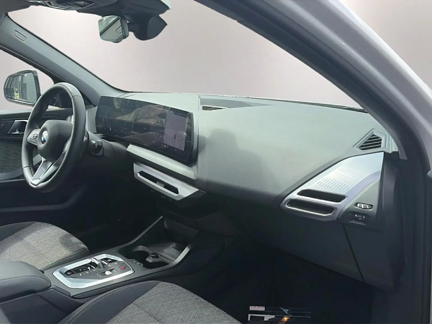 Intérieur de BMW Série 1 120da 2025, vue côté passager, tableau de bord moderne avec écran large et volant cuir.
