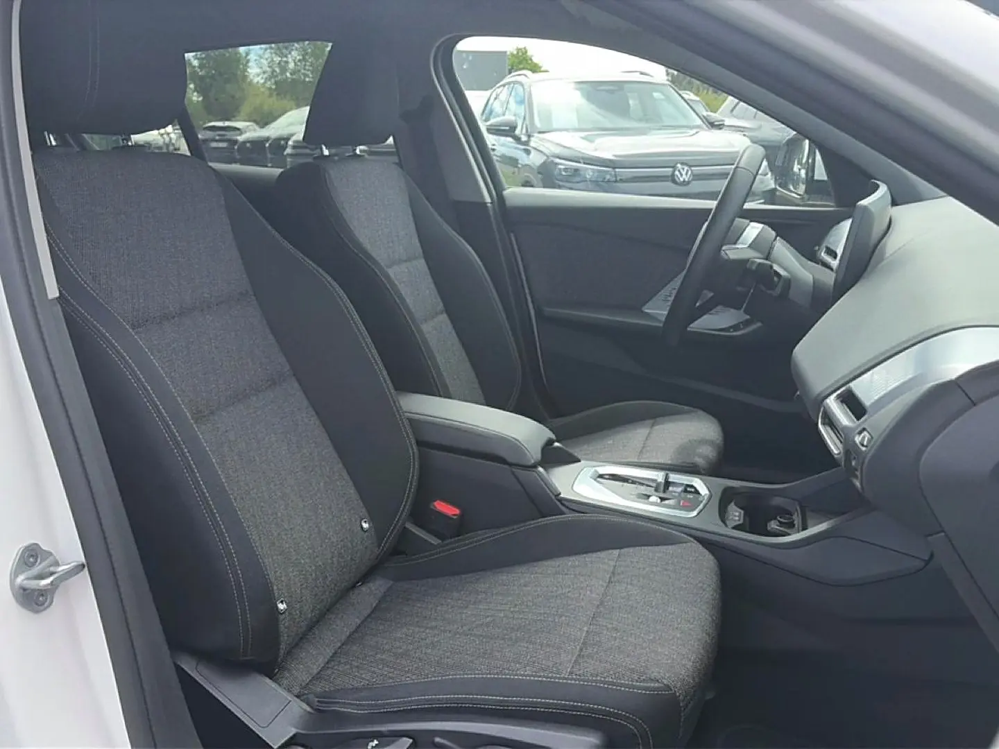 Vue intérieure côté conducteur de la BMW Série 1 blanche avec sièges sport gris et console centrale moderne.