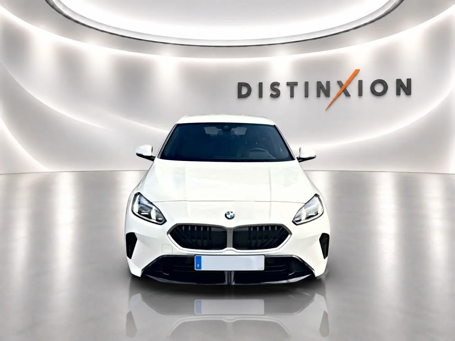 BMW Série 1 blanche vue de face, avec calandre noire et logo BMW sur fond lumineux studio Distinxion.