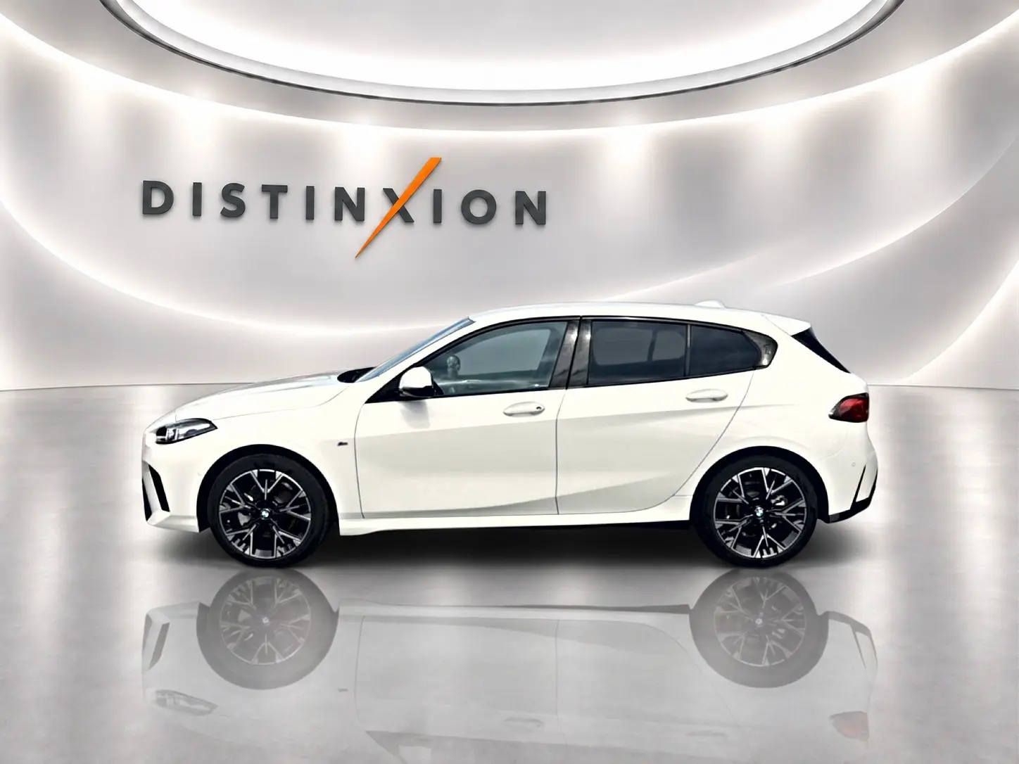 BMW Série 1 blanche vue de profil côté gauche, avec jantes noires et arrière compact en studio lumineux.
