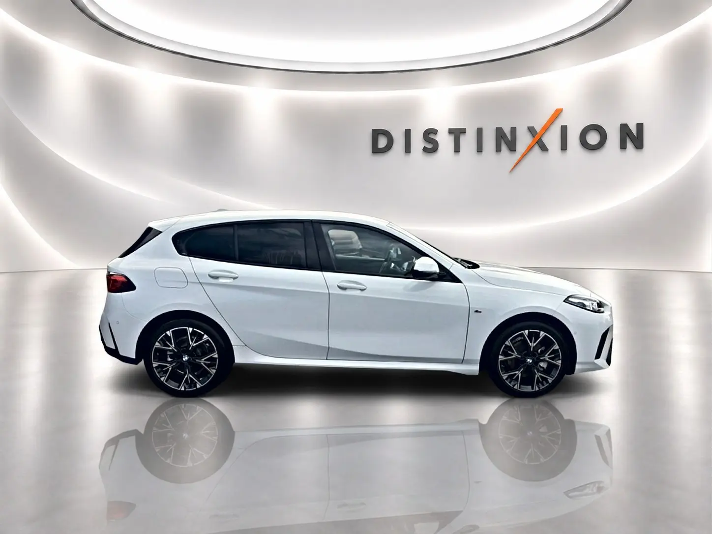 BMW Série 1 blanche vue de profil côté gauche dans un showroom lumineux avec jantes sport noires.