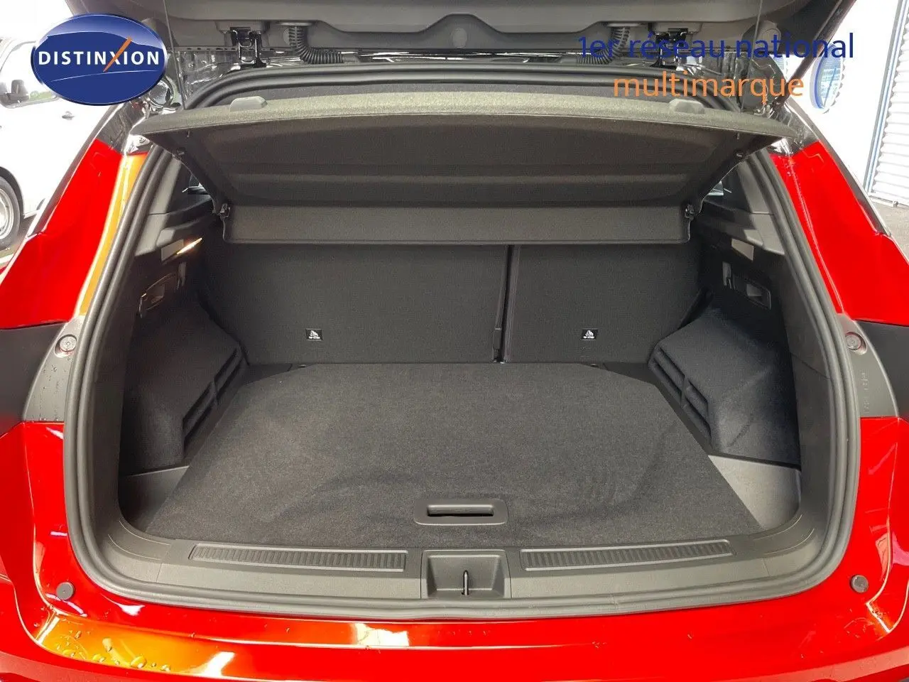 Coffre ouvert d'un Renault Austral E-Tech Full Hybrid rouge passion avec toit noir, vue arrière montrant l'espace de chargement vide.