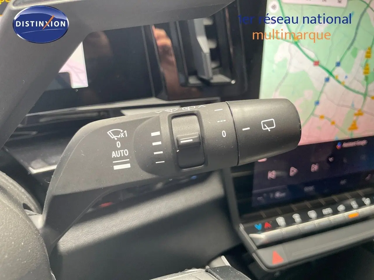 Gros plan sur la commande d'essuie-glace droite du Renault Austral E-Tech rouge passion, avec écran tactile et GPS en arrière-plan.