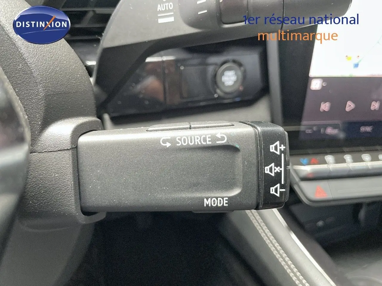 Gros plan sur la commande au volant du Renault Austral E-Tech rouge passion avec toit noir, montrant les boutons source et mode.