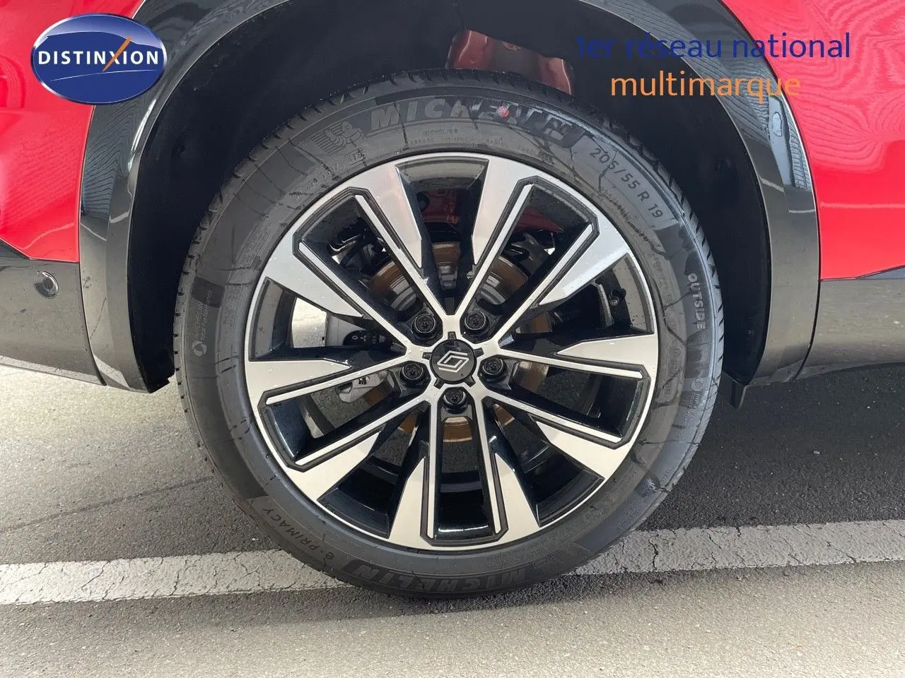 Gros plan sur la roue avant gauche du Renault Austral rouge passion avec jante alliage bicolore moderne.