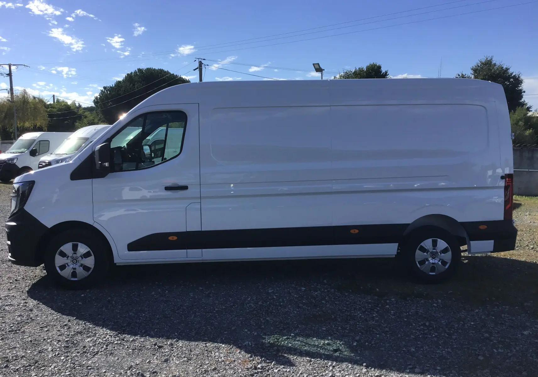 Profil côté gauche d’un fourgon blanc Renault Master L3H2 2025 avec protections latérales noires et jantes acier.