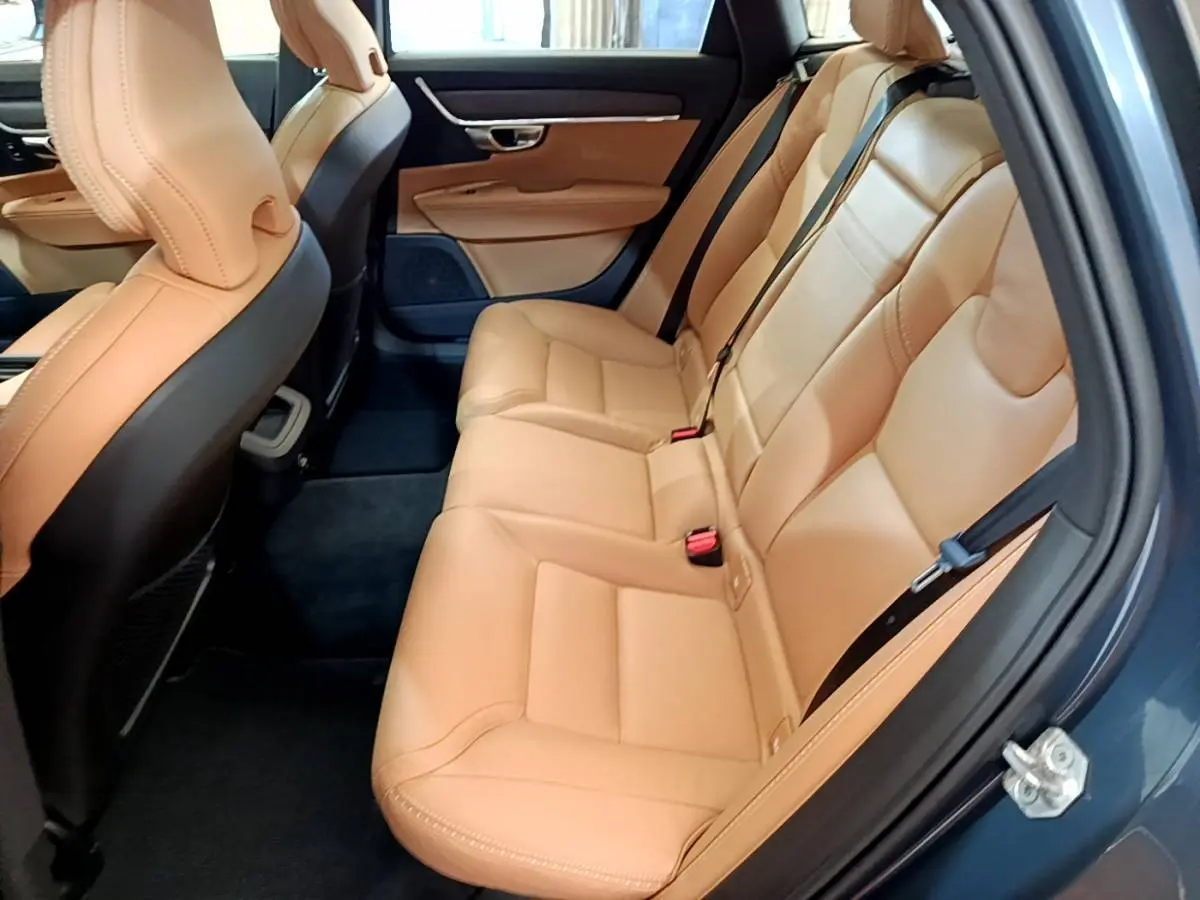 Vue côté droit de l'intérieur arrière du Volvo V90 Cross Country 2019 avec sièges en cuir beige et portières bleu foncé.