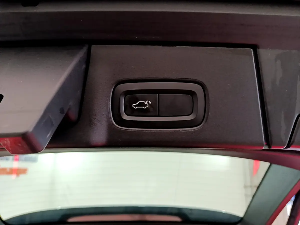 Bouton d'ouverture électrique du coffre sur la partie intérieure du hayon d'un Volvo V90 Cross Country bleu.