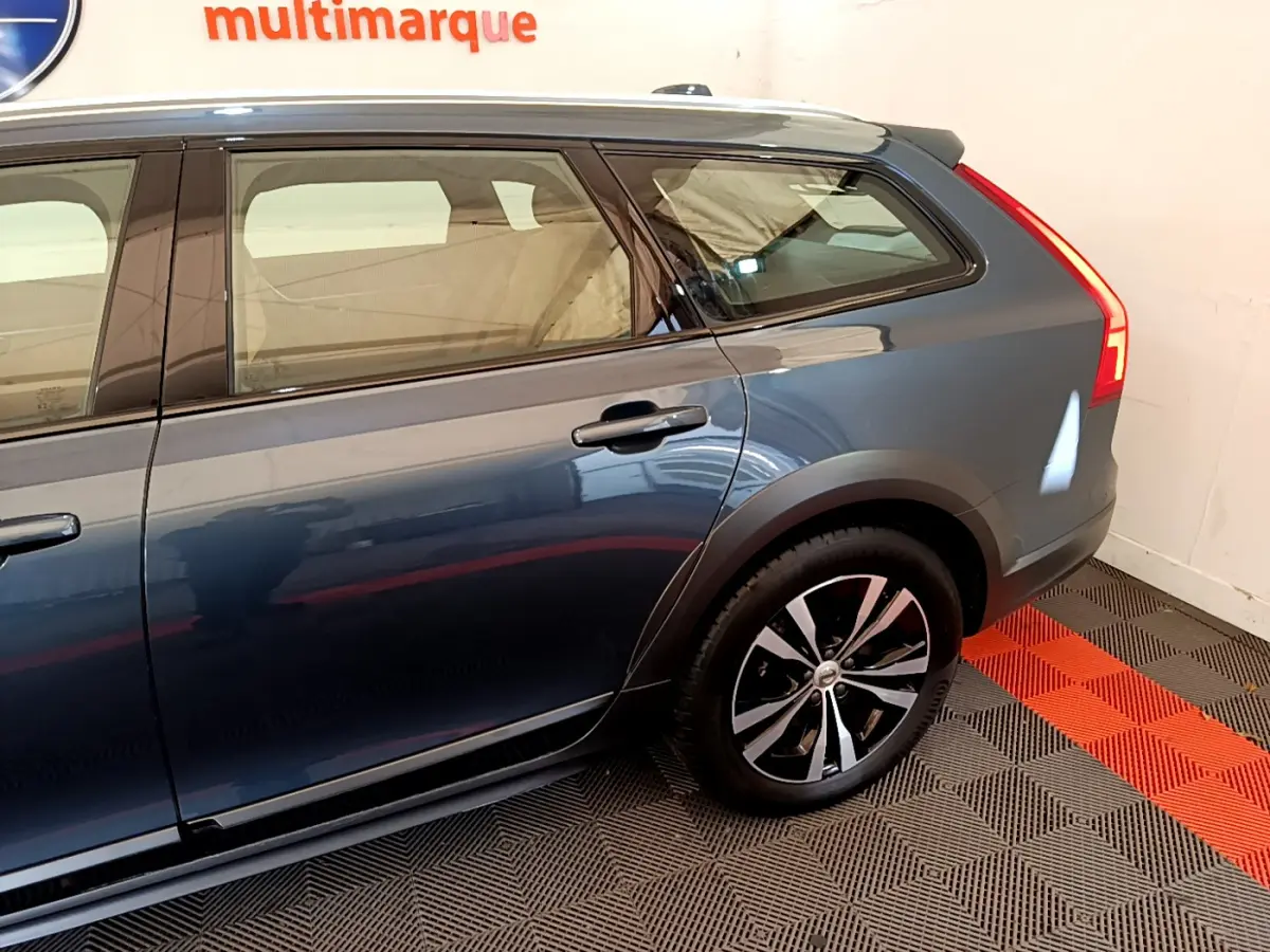 Vue latérale droite du Volvo V90 Cross Country bleu, mettant en valeur la roue arrière et les lignes élégantes du break.
