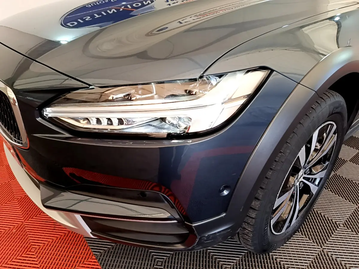 Gros plan sur l'avant droit bleu du Volvo V90 Cross Country 2019, mettant en valeur le phare LED et la jante alliage.