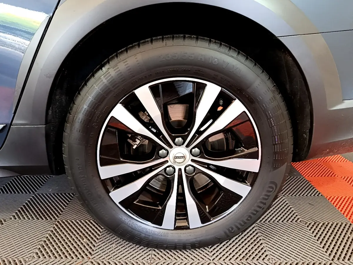 Gros plan sur la roue avant droite du Volvo V90 Cross Country bleu, jante alliage noir et argentée.