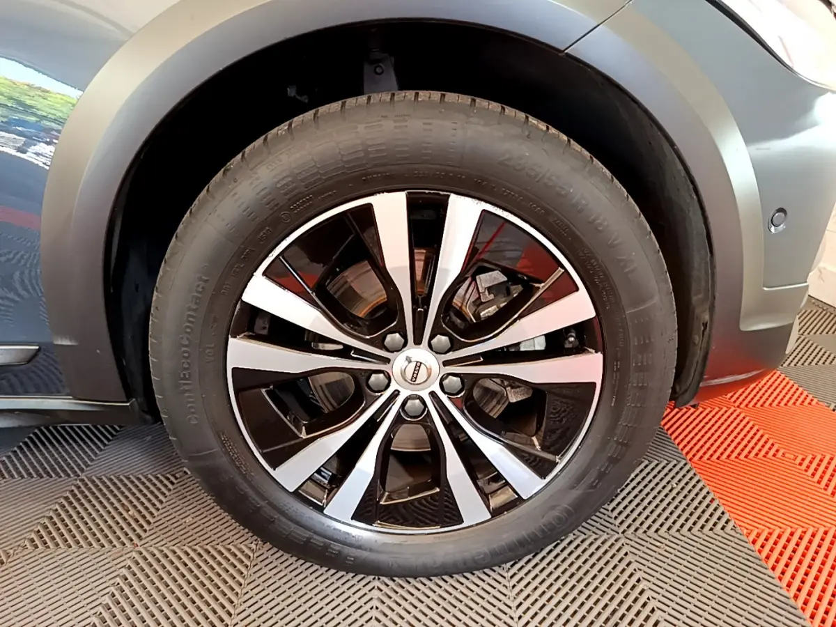 Gros plan sur la roue avant droite avec jante alliage bicolore du Volvo V90 Cross Country bleu 2019.