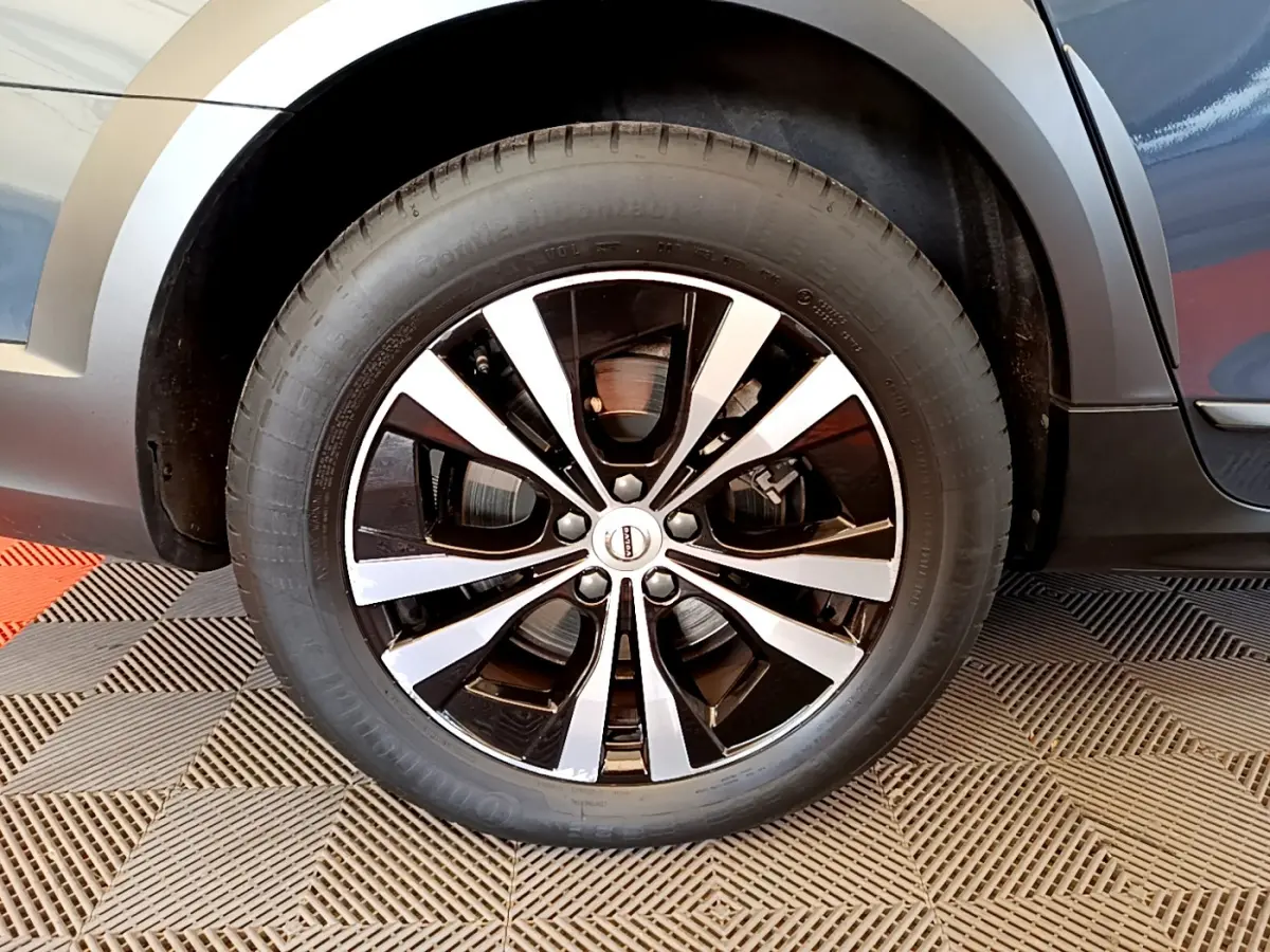 Gros plan sur la roue avant droite de la Volvo V90 Cross Country bleu, avec jante alliage noir et argentée.