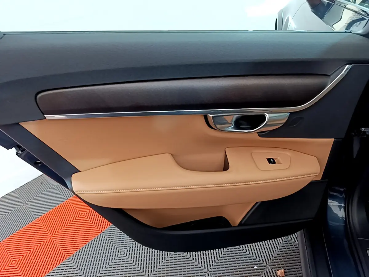 Vue rapprochée de la porte avant gauche beige et noire du Volvo V90 Cross Country bleu, avec poignée chromée.