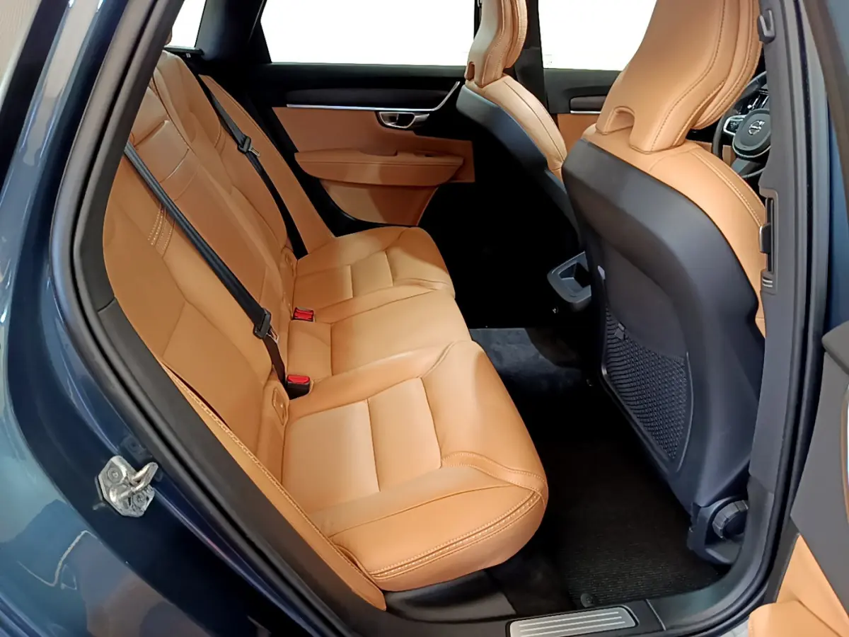 Vue intérieure côté gauche des sièges arrière en cuir beige du Volvo V90 Cross Country bleu, avec porte ouverte.