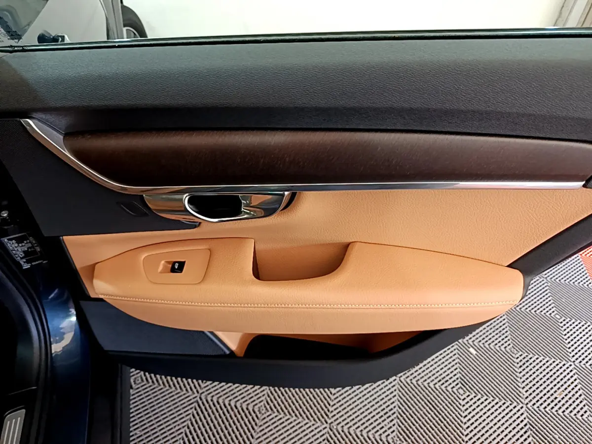 Intérieur côté gauche de la porte d’une Volvo V90 Cross Country bleu, garniture cuir beige et insert bois foncé.