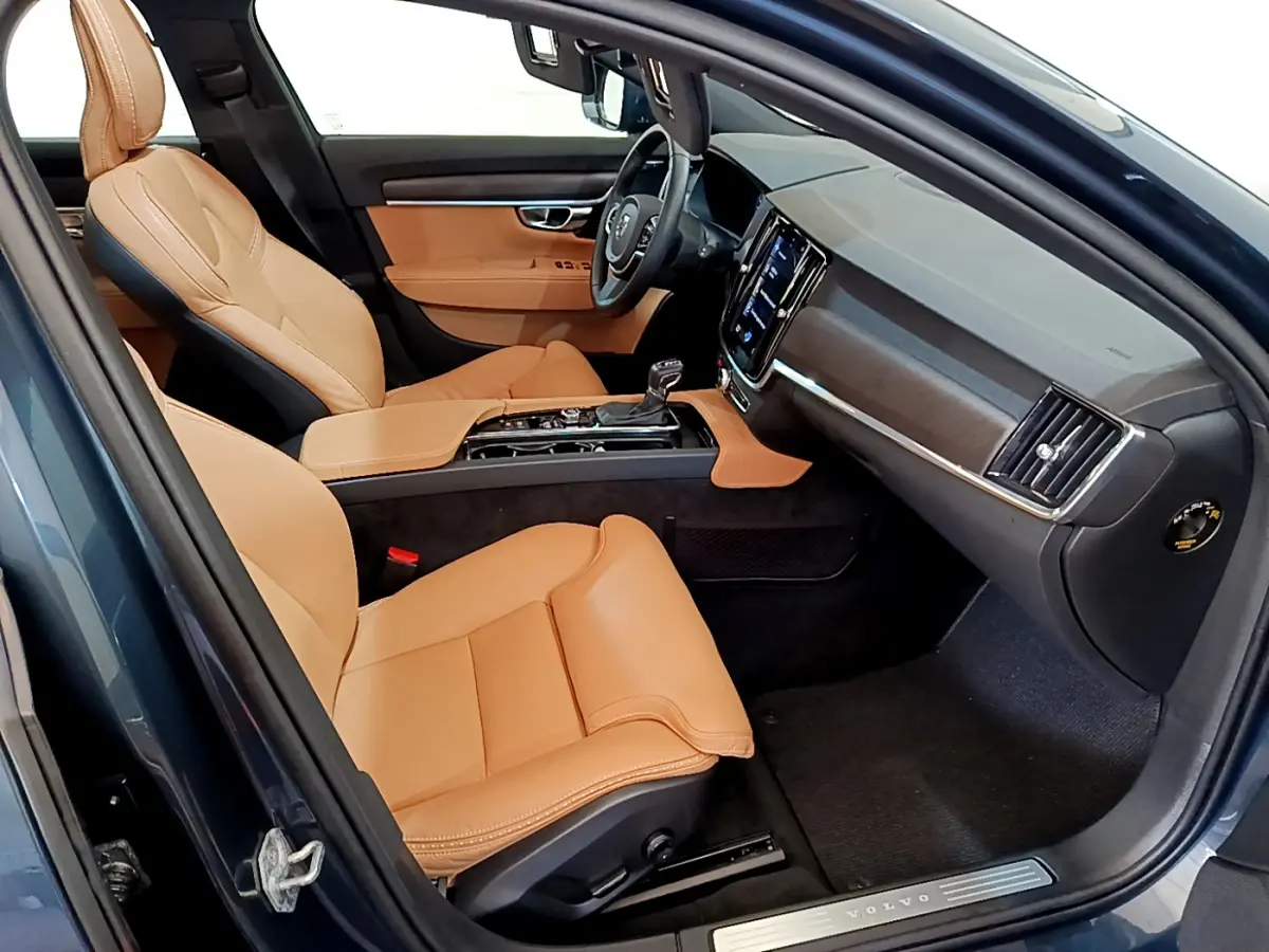 Intérieur avant droit du Volvo V90 Cross Country bleu, sièges cuir beige et tableau de bord moderne avec écran tactile.