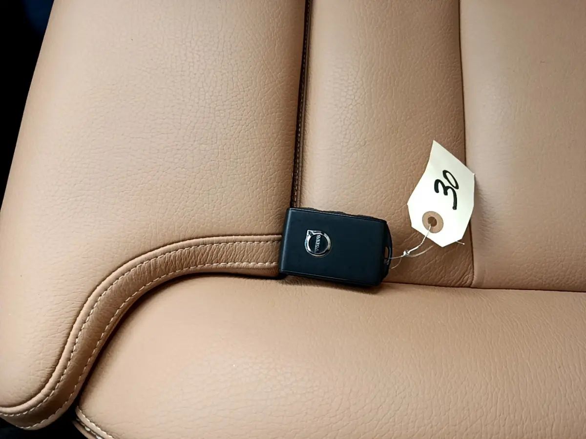 Gros plan sur une clé Volvo noire posée sur un siège en cuir beige clair, intérieur du Volvo V90 Cross Country.