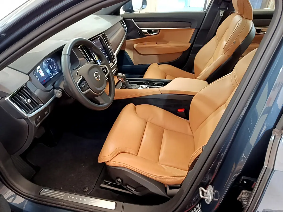 Vue intérieure côté conducteur de la Volvo V90 Cross Country bleu, sièges cuir beige et tableau de bord moderne.