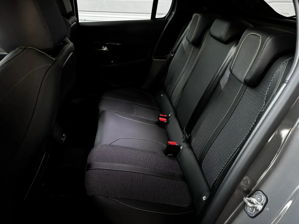 Vue côté droit de la banquette arrière en cuir noir avec surpiqûres vertes de la Peugeot 208 Hybrid 136 eDCS6 GT gris foncé.