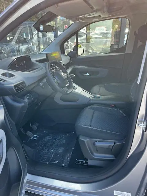 Vue intérieure côté conducteur du Peugeot Rifter gris foncé 2024, avec volant multifonction et tableau de bord digital.