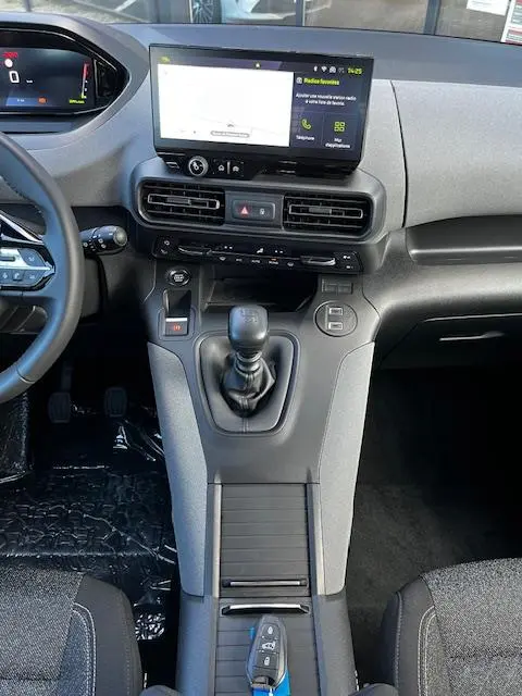 Vue intérieure centrée sur la console centrale et levier de vitesse manuelle du Peugeot Rifter gris foncé 2024.
