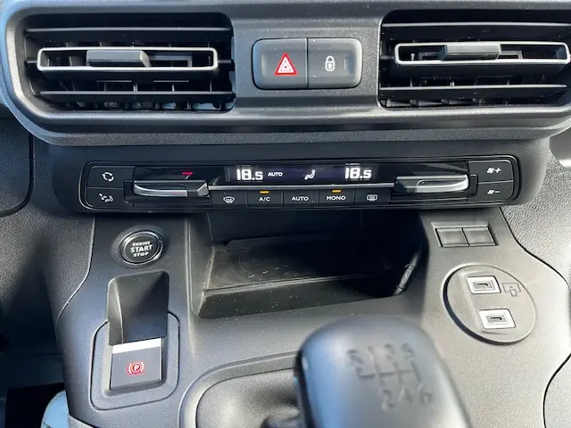 Vue rapprochée de la console centrale noire du Peugeot Rifter 2024 avec climatisation digitale et bouton start/stop.