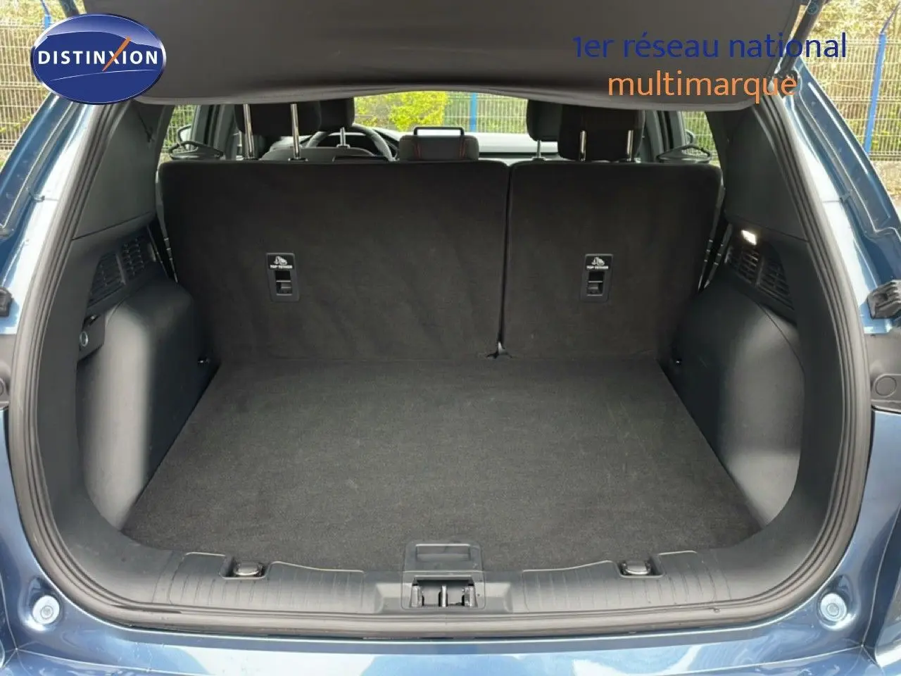 Coffre ouvert vu de l'arrière d'un Ford Kuga 2024 bleu vapor metal, montrant un espace de chargement propre et spacieux.