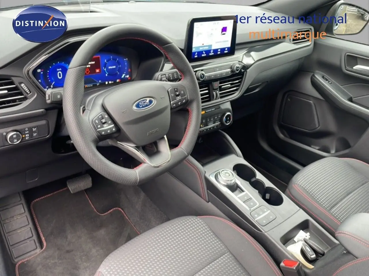 Vue intérieure côté conducteur du Ford Kuga 2024, volant cuir perforé avec surpiqûres rouges et console centrale moderne.