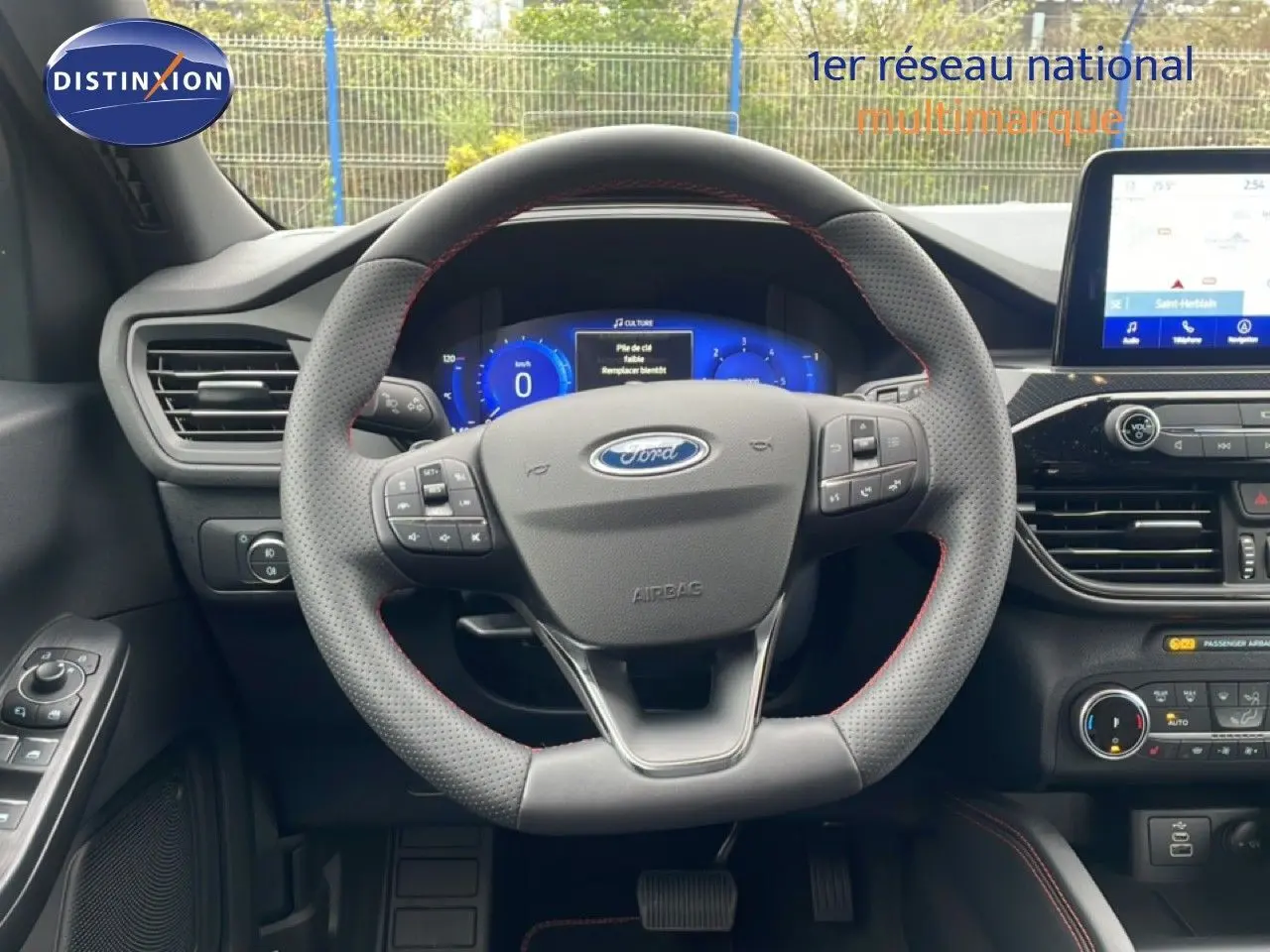 Vue intérieure centrée sur le volant perforé du Ford Kuga 2024 avec tableau de bord numérique et écran tactile.