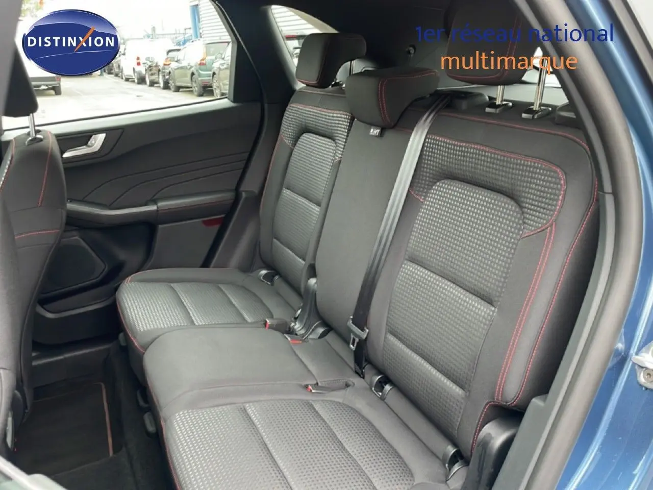 Vue intérieure côté droit des sièges arrière en tissu noir avec surpiqûres rouges du Ford Kuga 2024 bleu Vapor Metal.