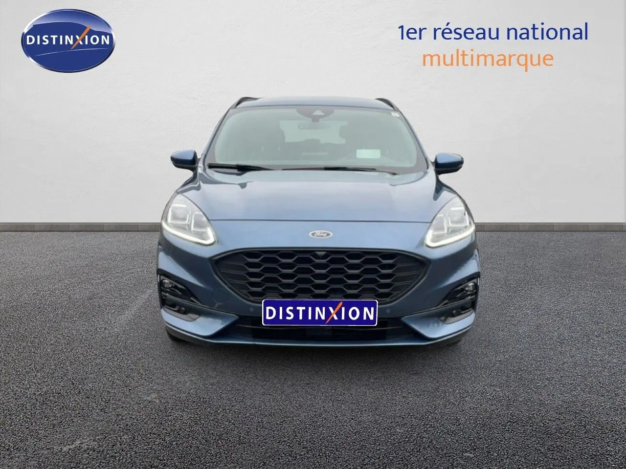 Vue frontale d’un Ford Kuga 2024 bleu Vapor Metal avec calandre noire et phares LED allumés.