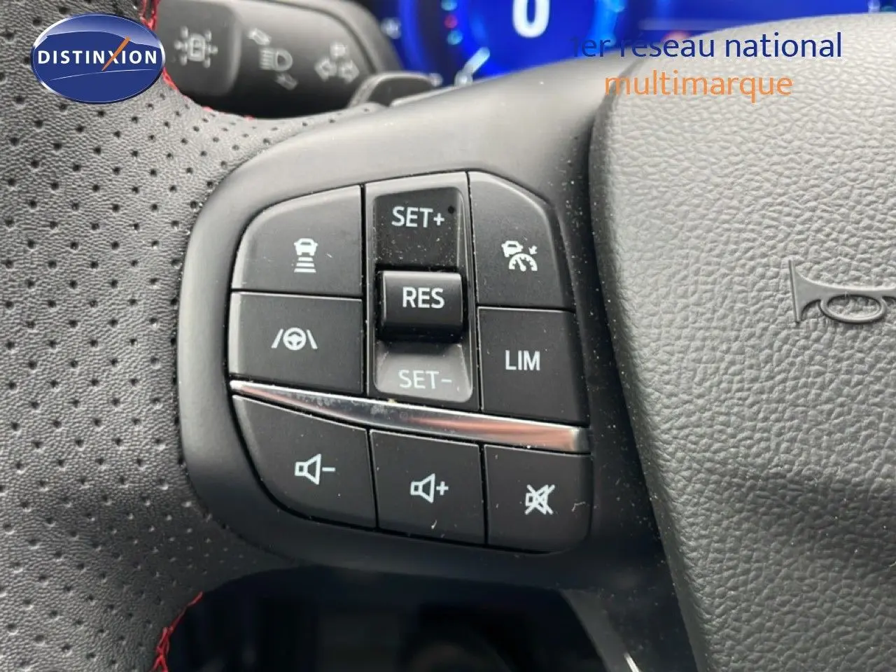 Gros plan sur les commandes au volant du Ford Kuga 2024 bleu Vapor Metal, avec boutons de régulateur et volume sonore.