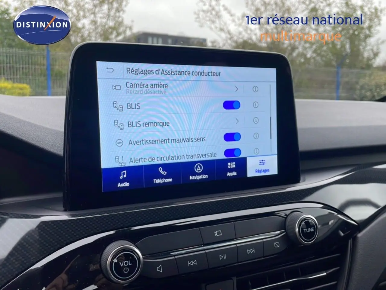 Vue intérieure centrée sur l'écran tactile du tableau de bord du Ford Kuga 2024, affichant les réglages d'assistance conducteur.