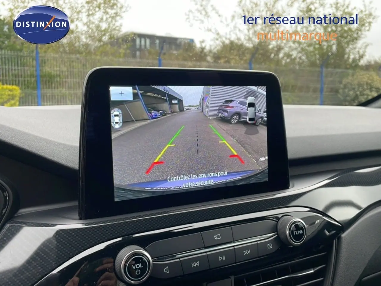 Écran central montrant la caméra de recul du Ford Kuga bleu Vapor Metal, avec vue arrière et lignes de guidage colorées.