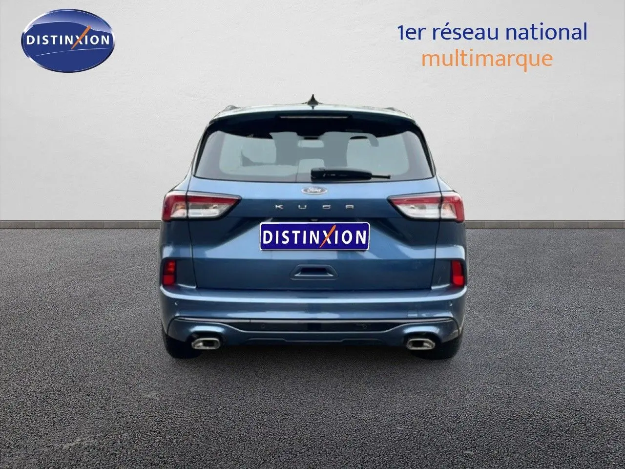 Vue arrière d'un Ford Kuga 2024 bleu Vapor Metal avec double sortie d'échappement et logo Distinxion visible.